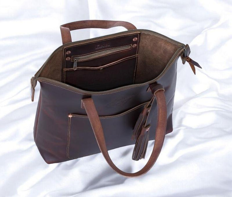 A brown leather tote bag is open, revealing its spacious interior and elegant design.