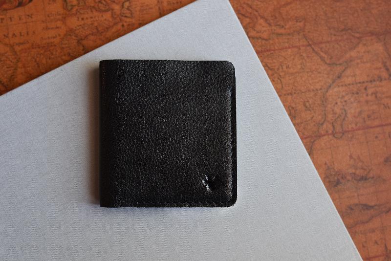 A sleek black leather wallet resting on a detailed map, perfect for travel planning and adventures.