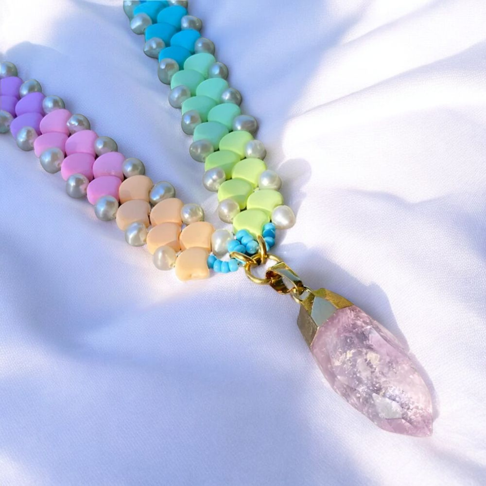 A vibrant rainbow-colored necklace featuring a striking crystal point at its center.