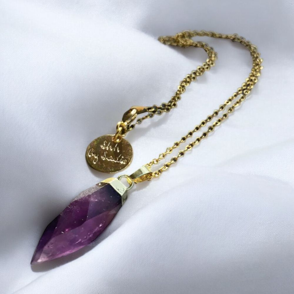 A purple stone necklace elegantly paired with a gold chain, showcasing a blend of color and sophistication.