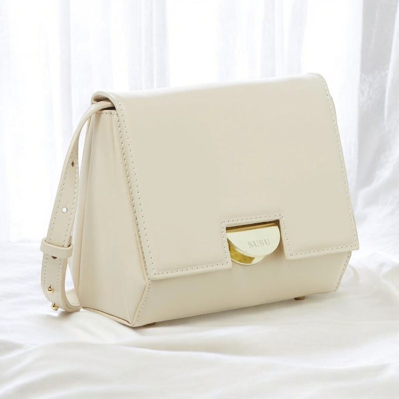 A chic cream leather crossbody bag, small in size, ideal for carrying essentials while maintaining a fashionable look.
