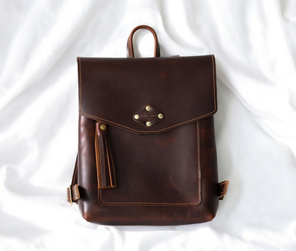 Stylish brown leather backpack featuring decorative tassels and studs, perfect for adding flair to any outfit.