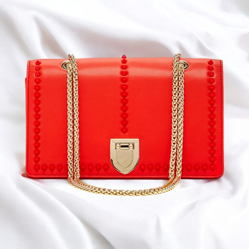 A stylish red purse featuring eye-catching studded detailing on the front, perfect for adding flair to any outfit.