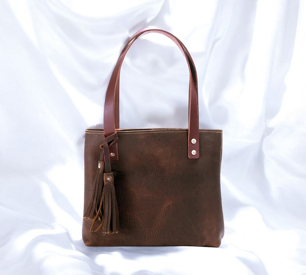 A luxurious brown leather tote bag adorned with a stylish tassel, exuding elegance and sophistication.