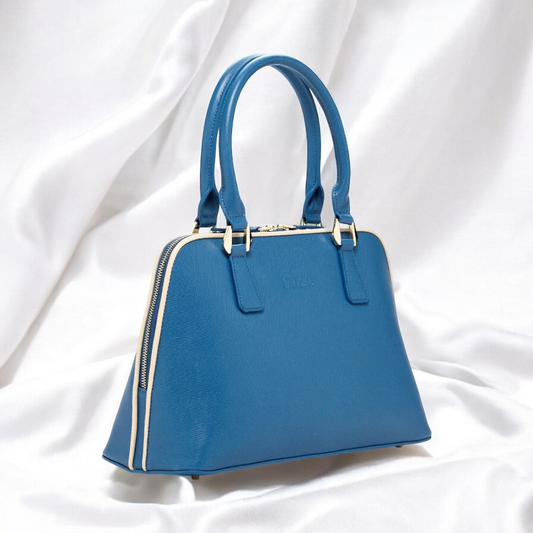 A chic blue handbag elegantly rests on a pristine white cloth, showcasing its vibrant hue against the soft backdrop.