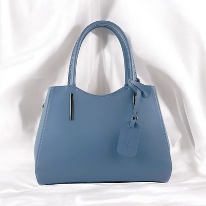 A blue leather handbag featuring a tag attached to it, showcasing its elegant design and craftsmanship.