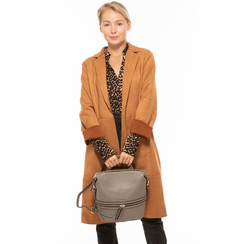 A woman wearing a coat and a leopard print shirt holds a stylish bag, showcasing a fashionable urban look.