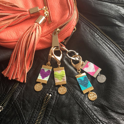 A stylish purse featuring a prominent key chain in for colors, showcasing a chic accessory ensemble.