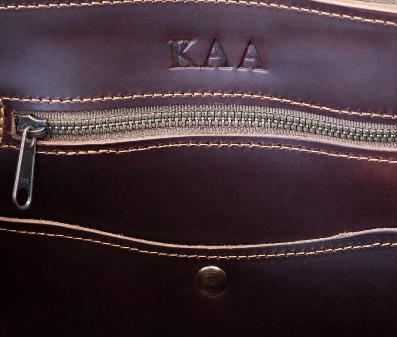 The interior of a sophisticated brown leather bag showcasing the elegant embossing of 'KAA". A glimpse of luxury and style.