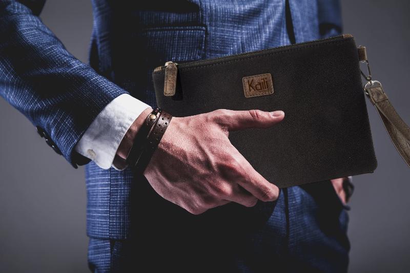 A man in a suit is holding a sleek black leather wallet in his hand, looking confident and professional.