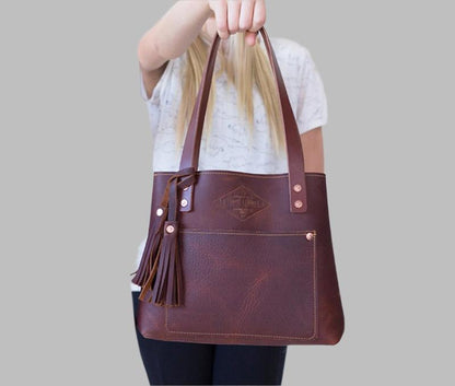 A luxurious cognac leather tote bag adorned with a stylish tassel, exuding elegance and sophistication.