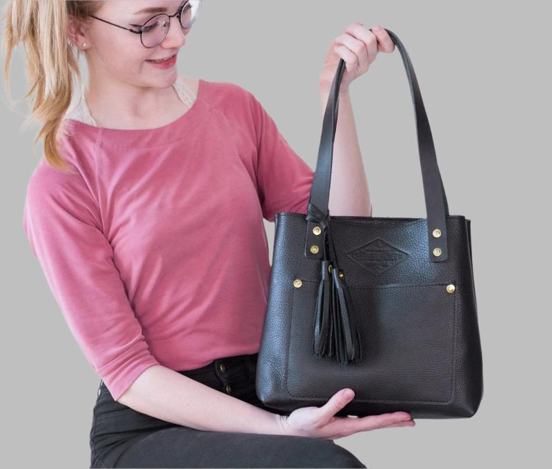 A luxurious black leather tote bag adorned with a stylish tassel, exuding elegance and sophistication.