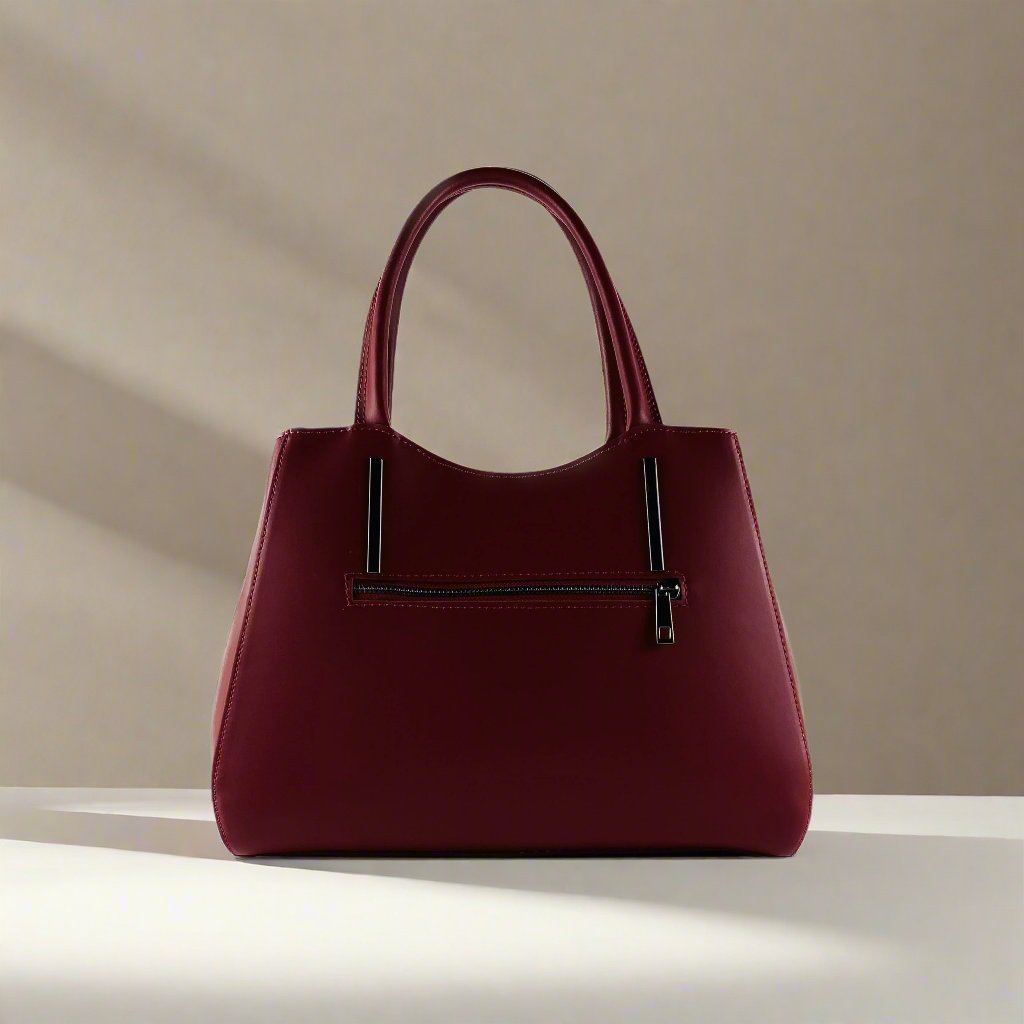 A luxurious burgundy leather handbag elegantly displayed against a pristine white background, showcasing its exquisite craftsmanship.