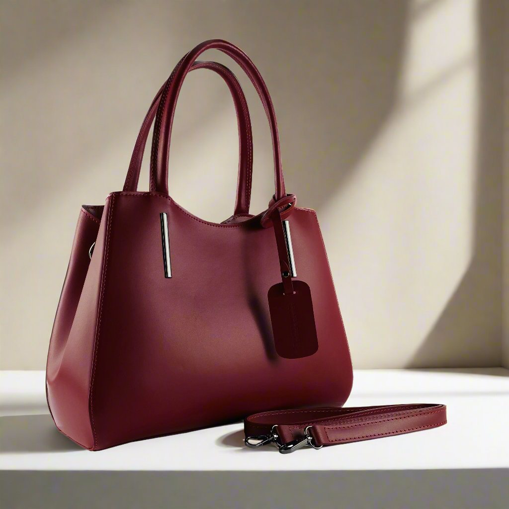 A luxurious burgundy leather handbag elegantly displayed against a pristine white background, showcasing its exquisite craftsmanship.