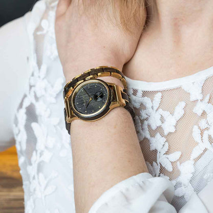 A woman in a white lace top elegantly displays a gold watch on her wrist.