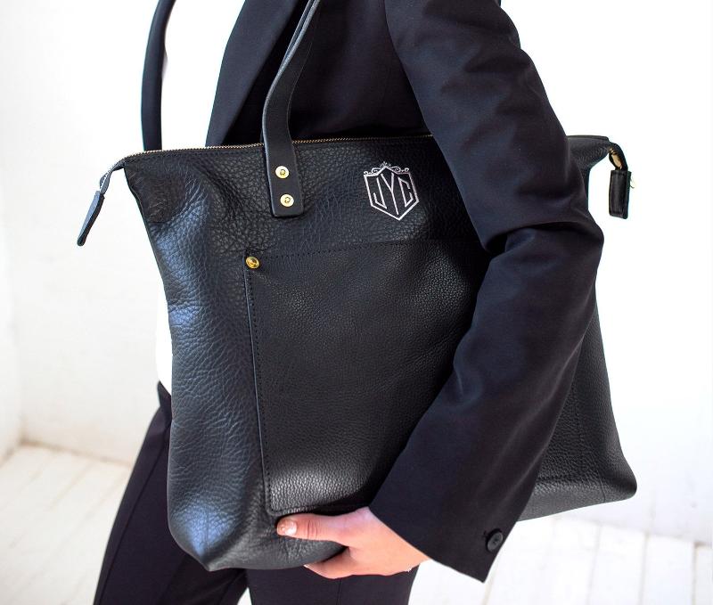 Elegant black leather tote bag featuring a sophisticated brown handle, perfect for a chic and stylish look.