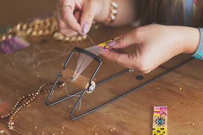 A person skillfully threads a needle to create a colorful bracelet, showcasing their craftsmanship and creativity.