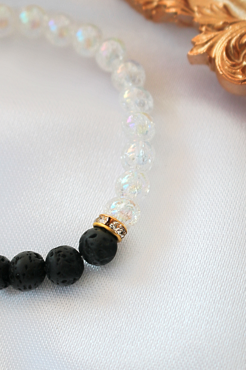 Black and white bracelet adorned with gold beads, showcasing a stylish and elegant design.

