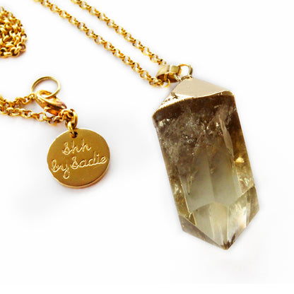 A gold plated necklace featuring a large, sparkling crystal pendant, elegantly designed for a luxurious look.