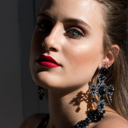 A woman wearing bold red lipstick and stylish earrings, showcasing her vibrant and confident look.