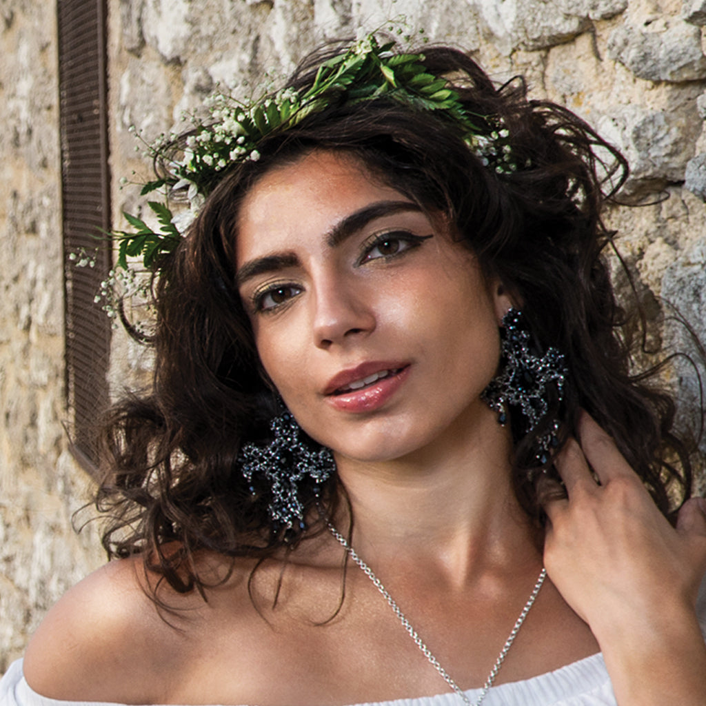 A woman with a vibrant flower crown and stylish earrings, radiating beauty and joy.