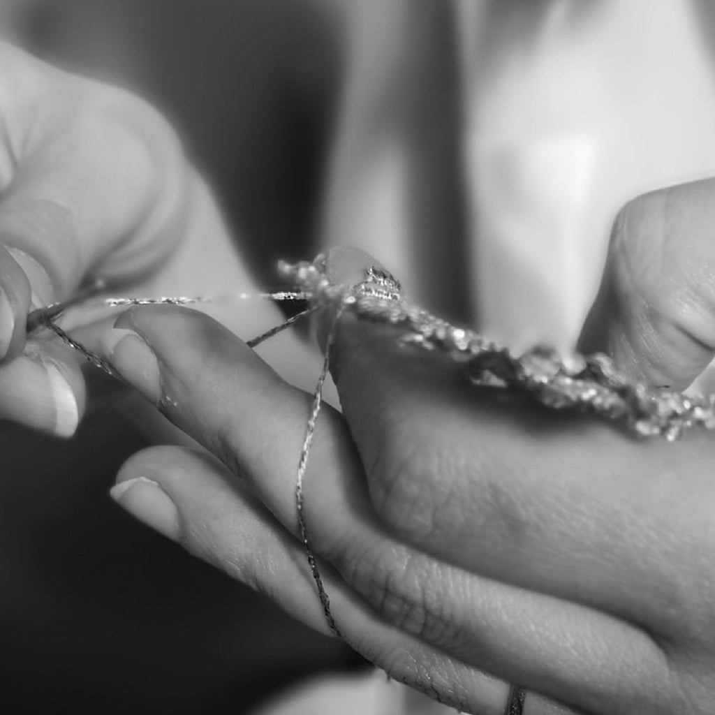 A woman elegantly displays a piece of jewelry in her hand, showcasing its intricate design and craftsmanship.