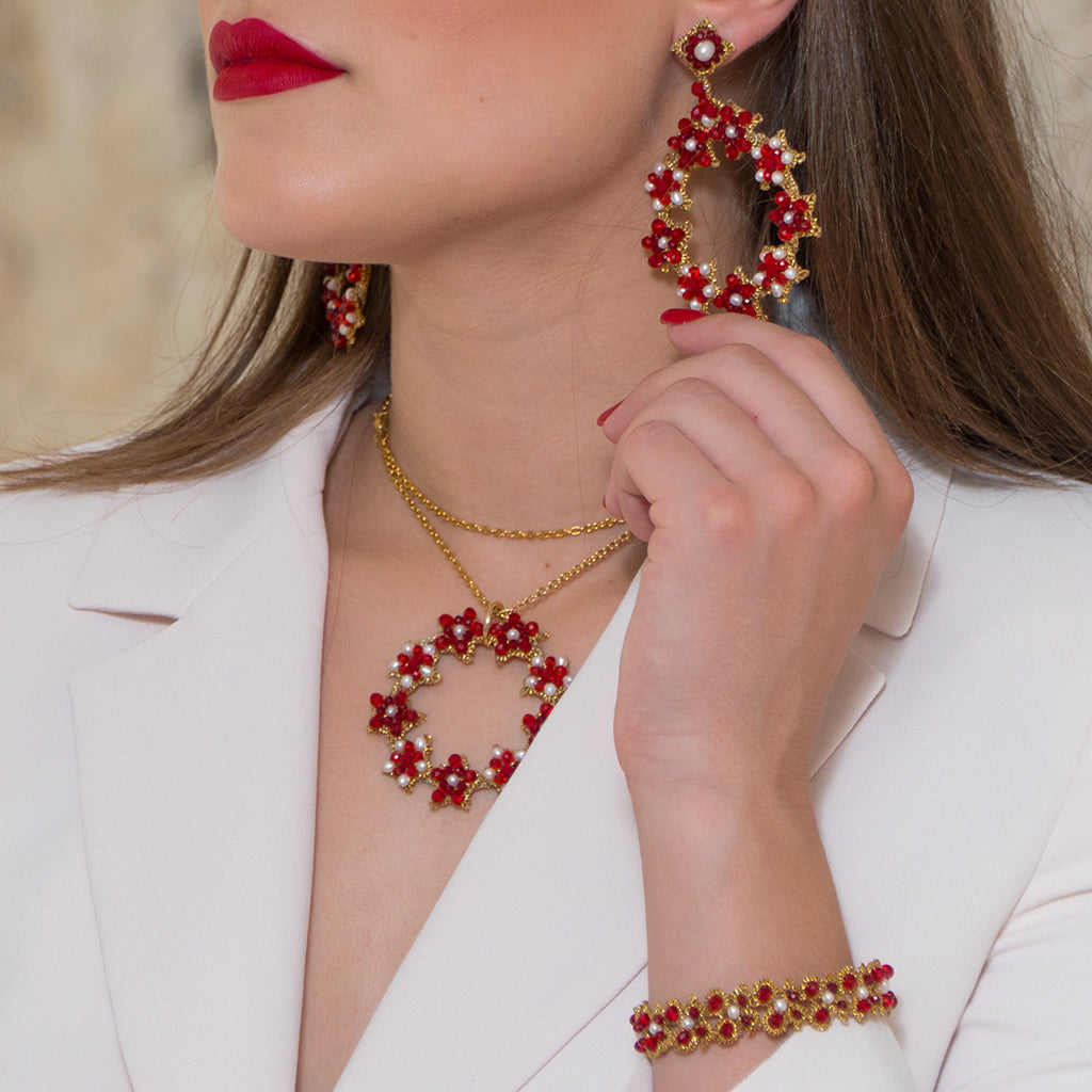 A woman in a white blouse showcases stunning red earrings, elegantly complementing her sophisticated look.