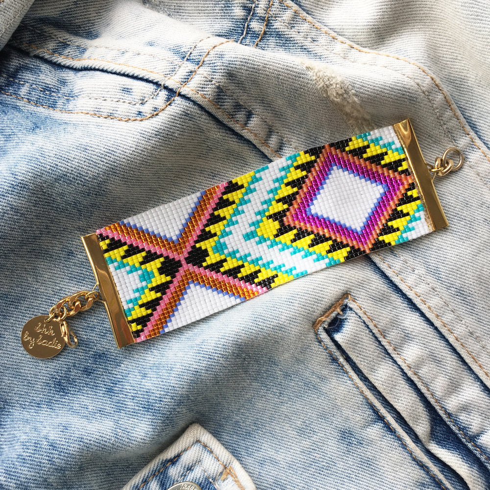 A vibrant beaded bracelet resting on a jeans, showcasing its colorful design and unique patterns.