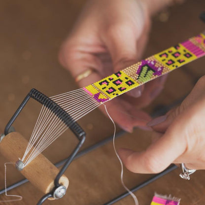 A skilled artisan delicately threads a needle to create a stunning bracelet, showcasing craftsmanship and elegance.