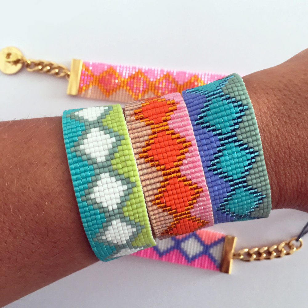 A woman's hand gracefully holds a vibrant bracelet adorned with an array of colorful beads.