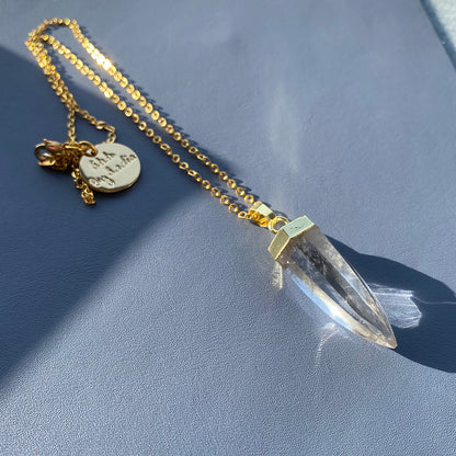 A clear quartz crystal pendant elegantly suspended on a delicate gold chain, showcasing its natural beauty and shine.