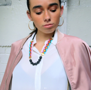 A woman in a pink jacket adorned with a necklace, exuding a stylish and confident appearance.