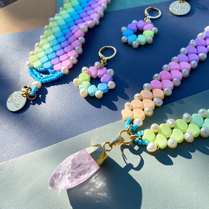 A vibrant rainbow-colored necklace featuring a striking crystal point at its center.