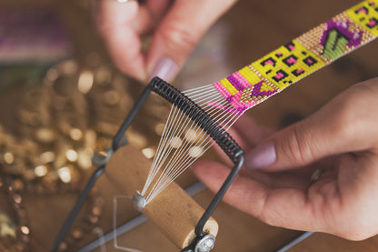 
A person sewing a colorful bracelet on a sewing machine, focused and creative in their craft.