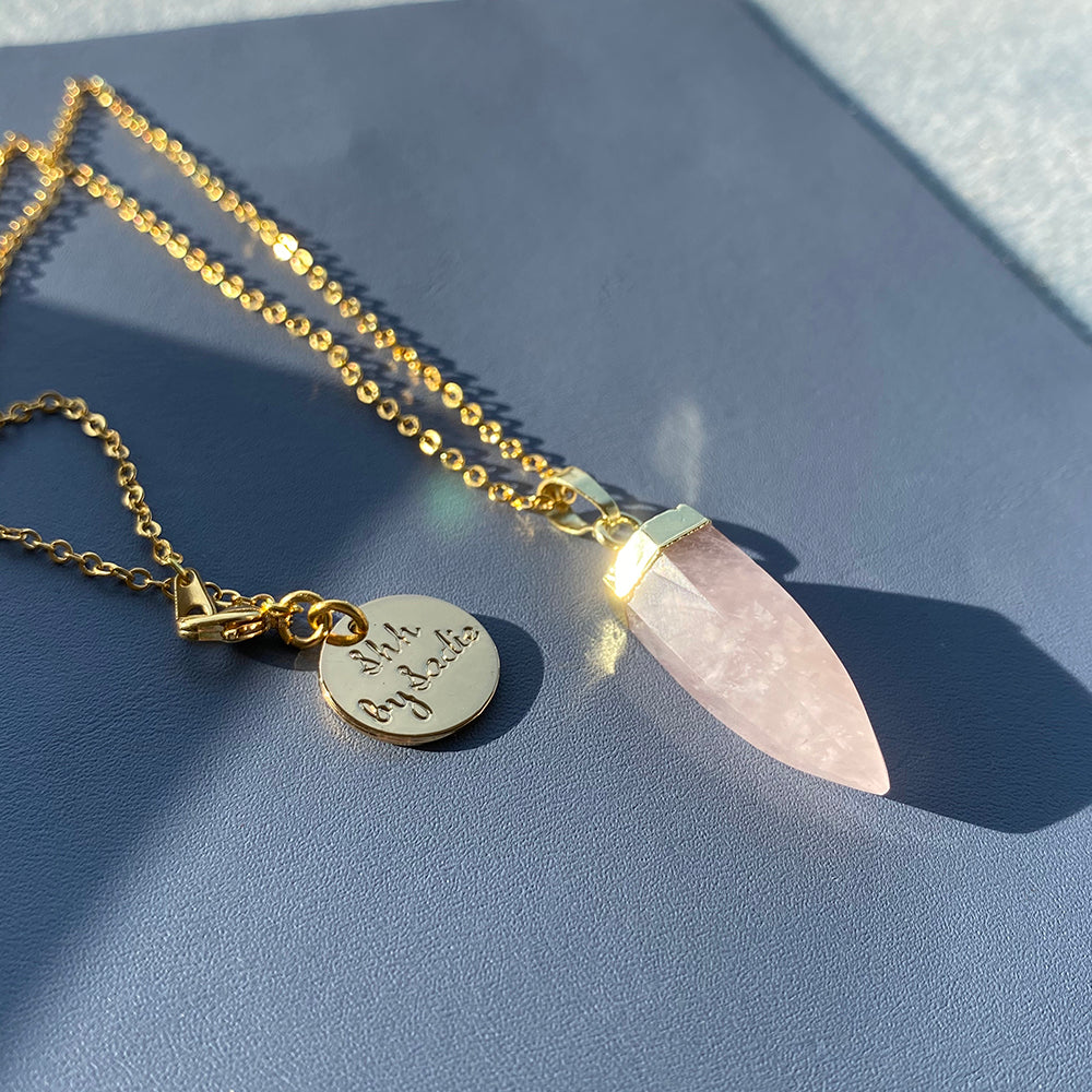 A pink quartz stone necklace elegantly paired with a gold-plated chain, showcasing a blend of color and luxury.