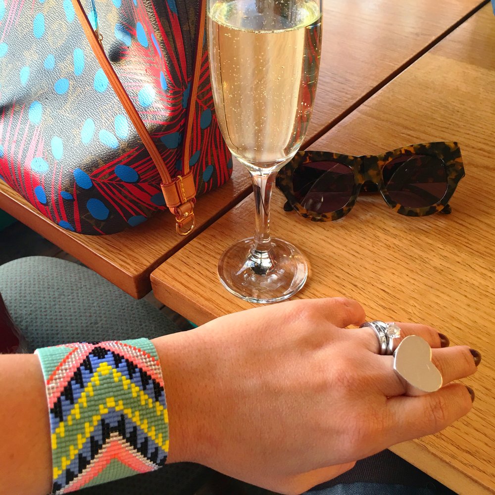 A women with a vibrant handmade bracelet raises a wine glass, enjoying a cheerful moment.