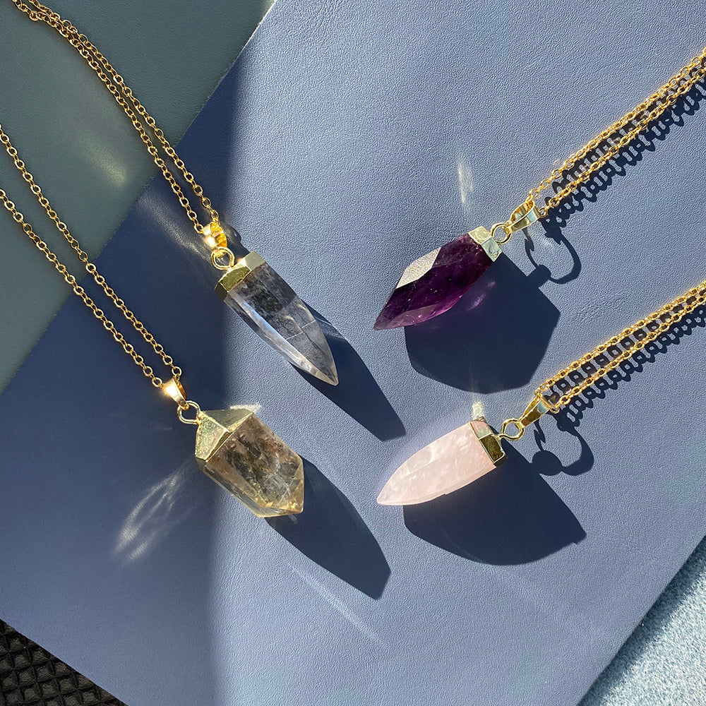 Three distinct crystal necklaces displayed against a blue background, showcasing their unique colors and designs.