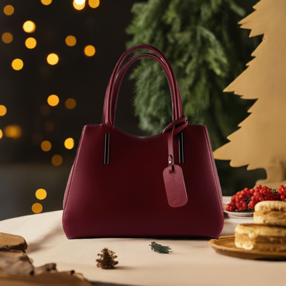 A luxurious burgundy leather handbag elegantly displayed against a pristine white background, showcasing its exquisite craftsmanship