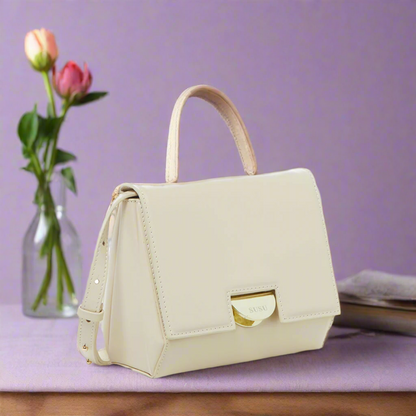 A chic cream leather crossbody bag, small in size, ideal for carrying essentials while maintaining a fashionable look.
