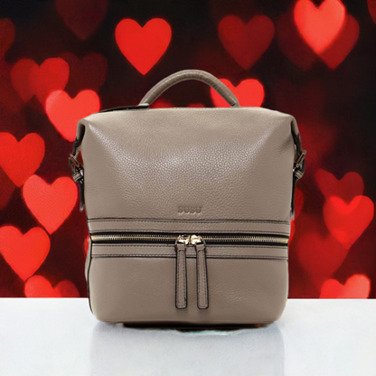 A small leather backpack sitting on a white table, the wall is black with red heart.  featuring two zippers, showcasing a sleek and stylish design suitable for everyday use. Valentine day gift.
