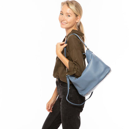 A stylish woman elegantly holds a chic blue handbag, showcasing her refined taste and fashion-forward sensibility.